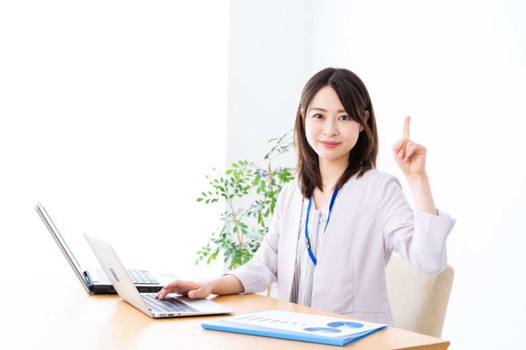 PCを見ながら人差し指を上げる女性